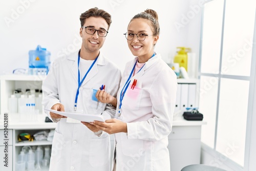 Man and woman wearing scientist uniform working at laboratory