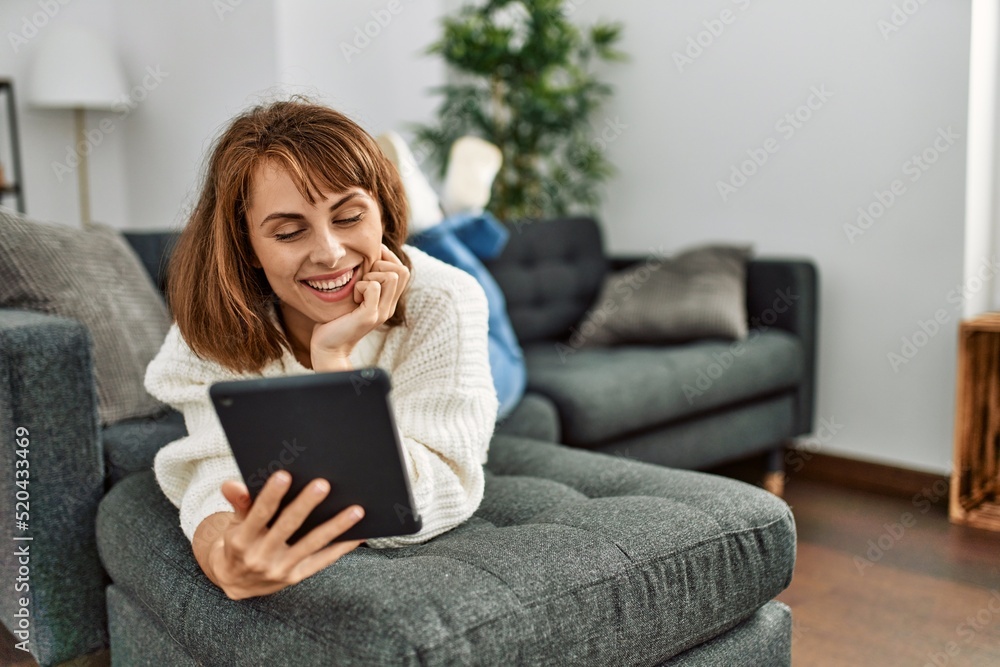 Young caucasian woman using touchpad lying on sofa at home Young caucasian woman using touchpad lying on sofa at home