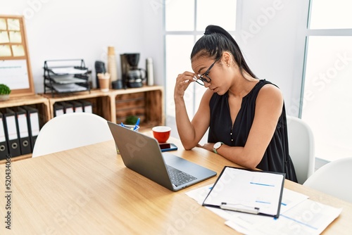 Young latin woman stressed working at office