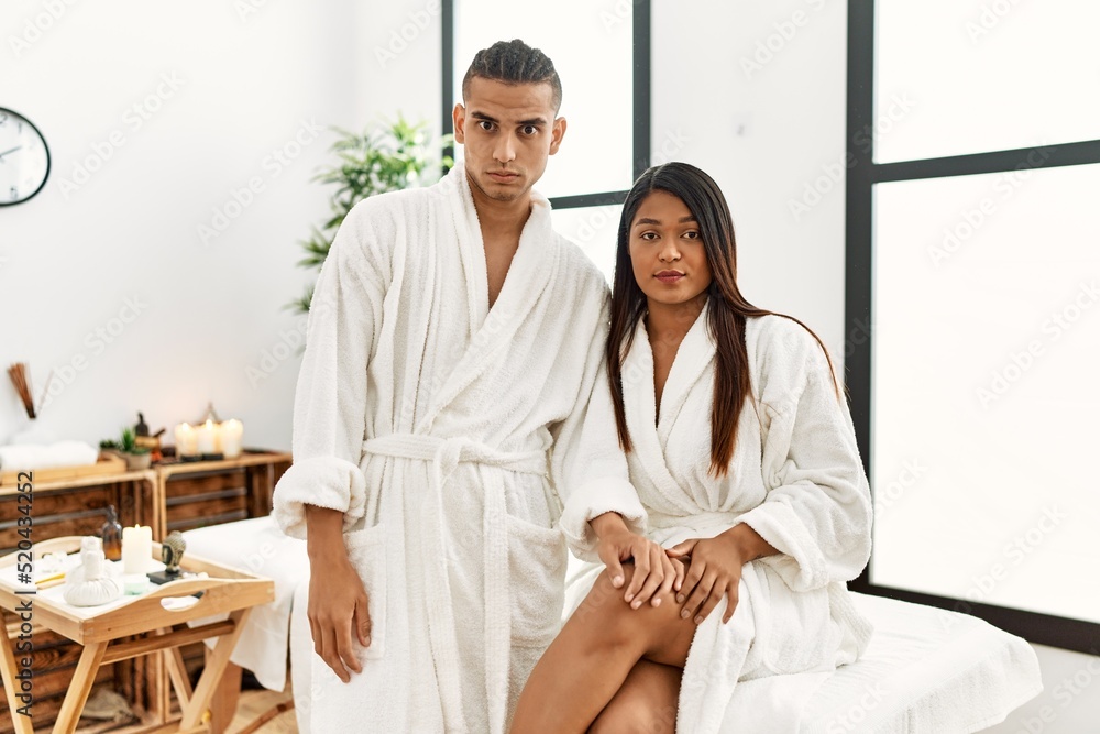 Obraz premium Young latin couple wearing towel standing at beauty center skeptic and nervous, frowning upset because of problem. negative person.