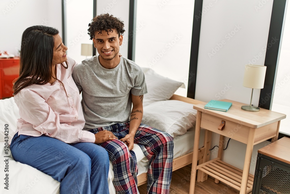 Young latin couple smiling happy sitting on the bed at bedroom.