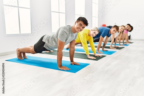 Group of young people smiling happy training yoga at sport center.