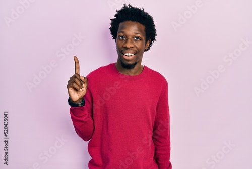 Young african american man wearing casual clothes pointing finger up with successful idea. exited and happy. number one.