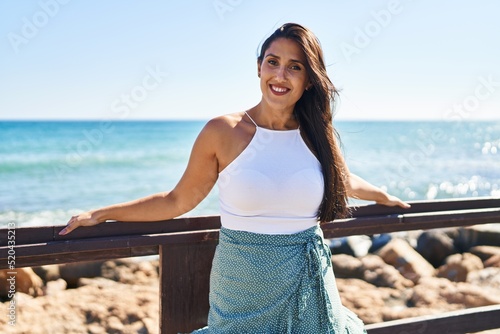 Canvastavla Young hispanic woman smiling confident leaning on balustrade at seaside