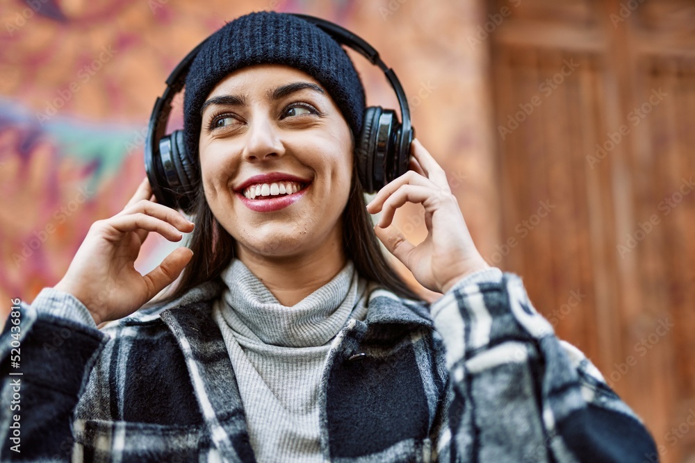 Young hispanic woman smiling happy using headphones at the city. Young hispanic woman smiling happy using headphones at the city.