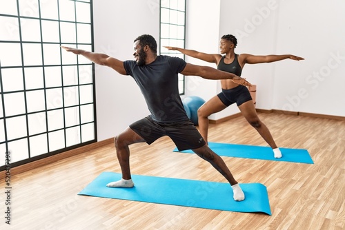 Young african american sporty couple smiling happy training yoga at sport center.