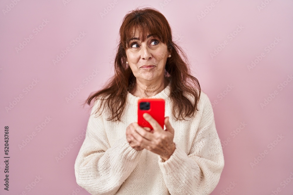 Middle age hispanic woman using smartphone typing message smiling looking to the side and staring away thinking. Middle age hispanic woman using smartphone typing message smiling looking to the side and staring away thinking.