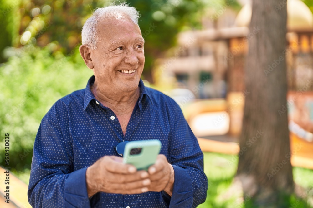 Senior grey-haired man smiling confident using smartphone at park Senior grey-haired man smiling confident using smartphone at park