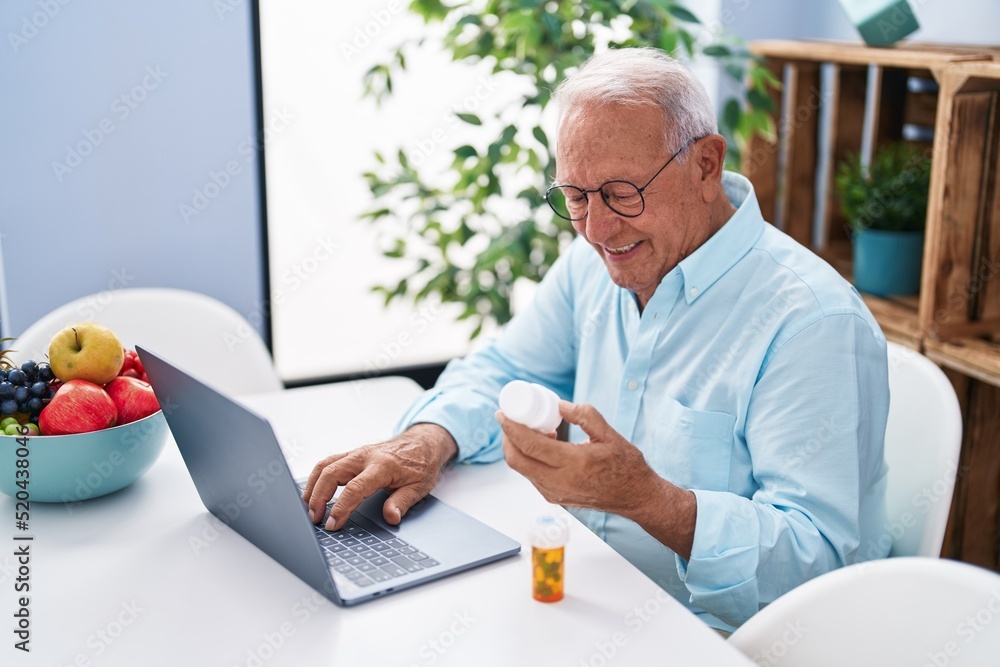 Senior grey-haired man having telemedicine sitting on table at home