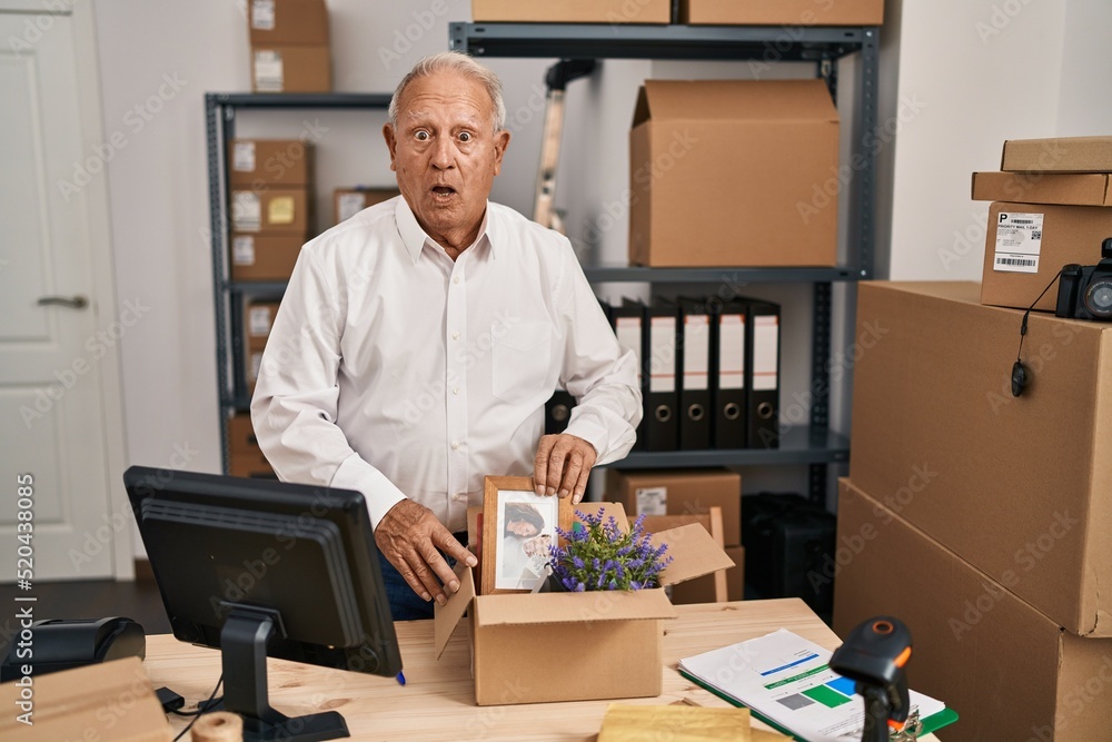 Senior man with grey hair working at small business ecommerce scared and amazed with open mouth for surprise, disbelief face Senior man with grey hair working at small business ecommerce scared and amazed with open mouth for surprise, disbelief face