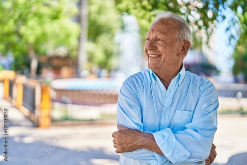 Senior grey-haired man smiling confident standing with arms crossed gesture at park