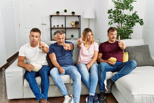 Group of middle age people sitting on the sofa at home pointing with finger up and angry expression, showing no gesture