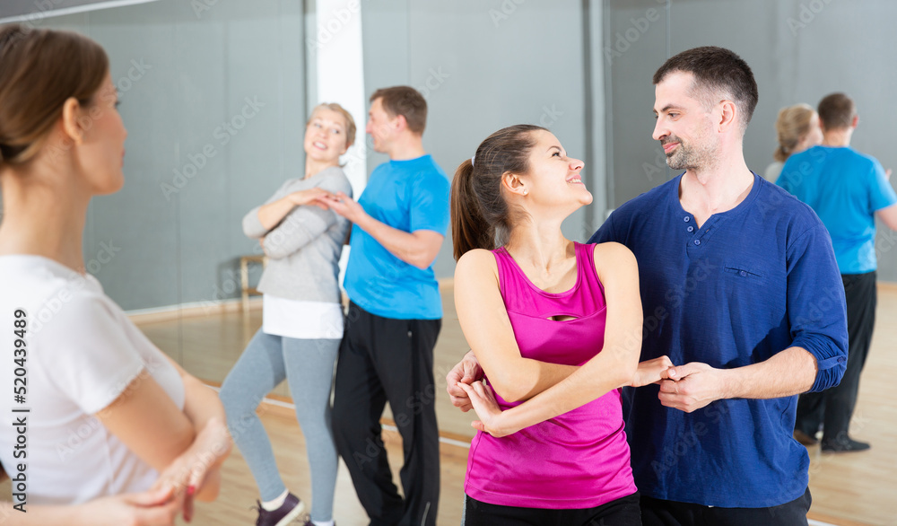 Young sporty woman enjoying bachata dance with partner in dancing class