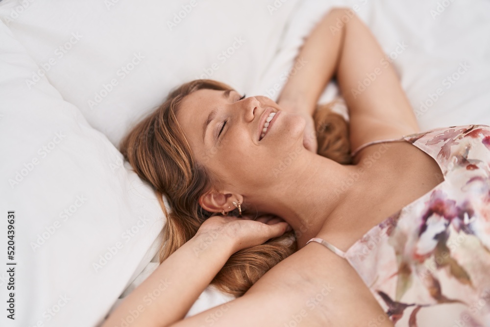 Young blonde girl lying on bed relaxed with hands on head at bedroom Young blonde girl lying on bed relaxed with hands on head at bedroom