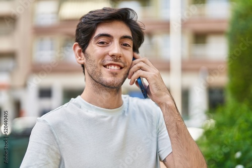 Young hispanic man smiling confident talking on the smartphone at street