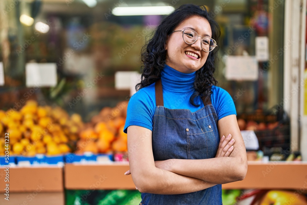 Young chinese woman employee smiling confident standing with arms crossed gesture at fruit store