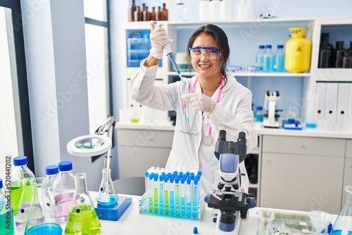 Young chinese woman wearing scientist uniform working at laboratory