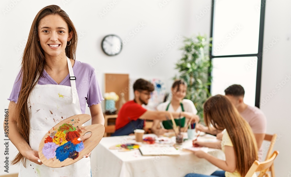 Obraz premium Group of people drawing sitting on the table. Woman smiling happy holding palette at art studio.