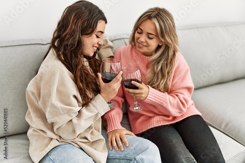 Young couple smiling happy toasting with red wine glass at home.