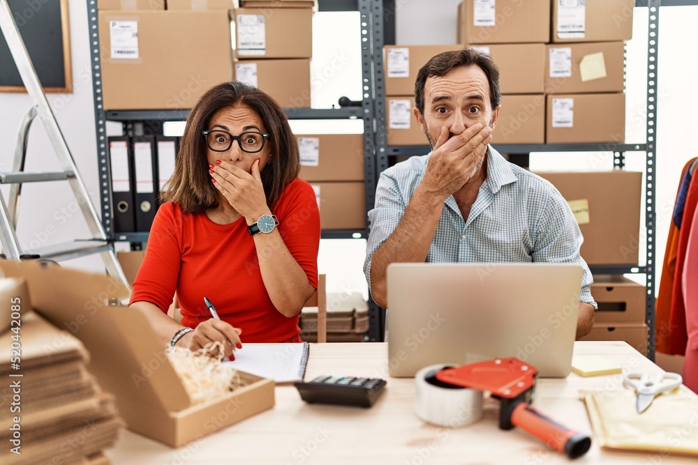 Middle age couple working at small business ecommerce shocked covering mouth with hands for mistake. secret concept. Middle age couple working at small business ecommerce shocked covering mouth with hands for mistake. secret concept.