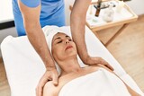 Middle age man and woman wearing therapist uniform having shoulders massage session at beauty center