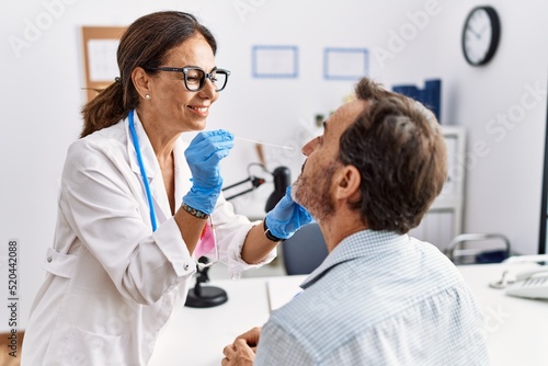 Middle age man and woman wearing doctor uniform making covid-19 test at clinic