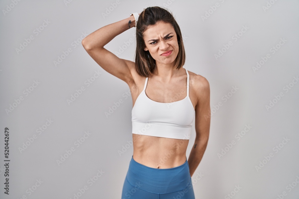 Hispanic woman wearing sportswear over isolated background confuse and wondering about question. uncertain with doubt, thinking with hand on head. pensive concept. Hispanic woman wearing sportswear over isolated background confuse and wondering about question. uncertain with doubt, thinking with hand on head. pensive concept.