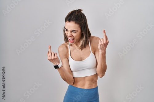 Hispanic woman wearing sportswear over isolated background showing middle finger doing fuck you bad expression, provocation and rude attitude. screaming excited © Krakenimages.com