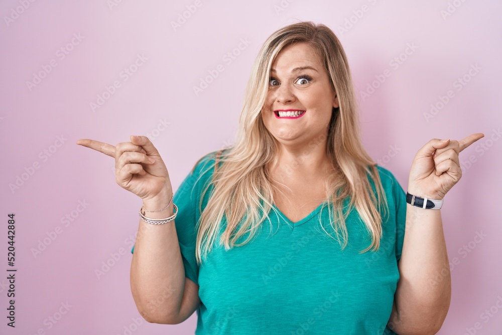 Caucasian plus size woman standing over pink background smiling confident pointing with fingers to different directions. copy space for advertisement Caucasian plus size woman standing over pink background smiling confident pointing with fingers to different directions. copy space for advertisement