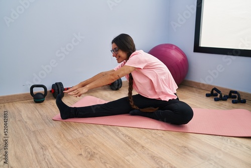 Young hispanic woman smiling confident stretching at sport center