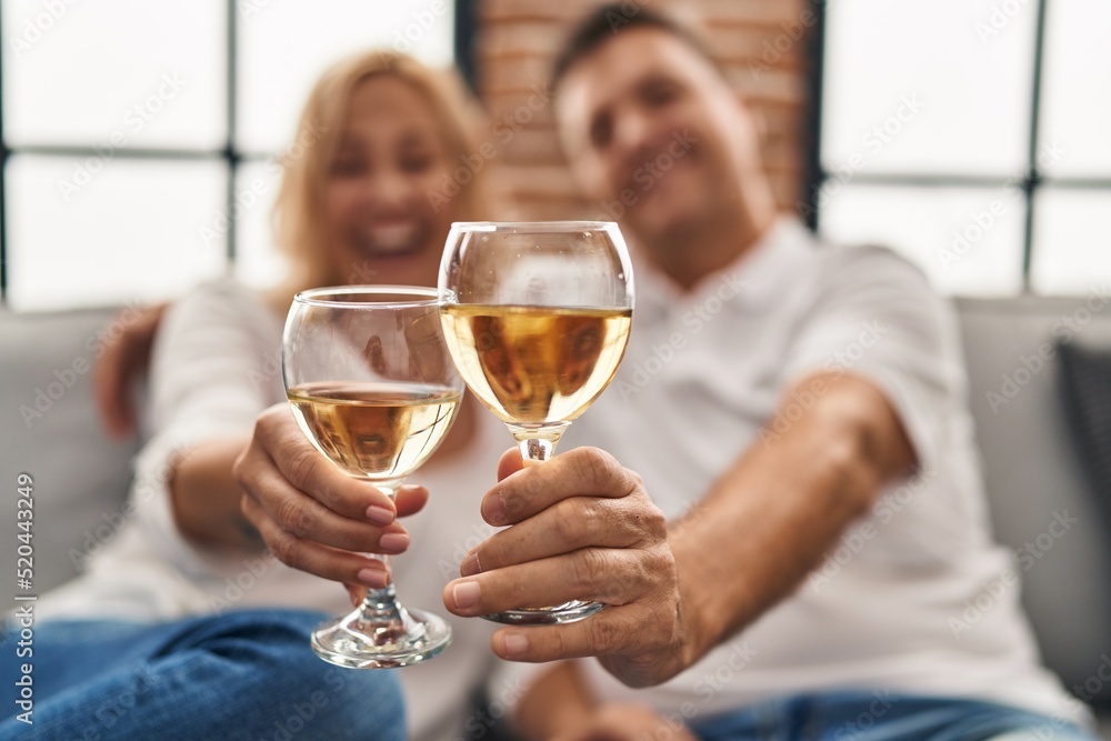 Middle age man and woman hugging each other toasting with champagne at home Middle age man and woman hugging each other toasting with champagne at home