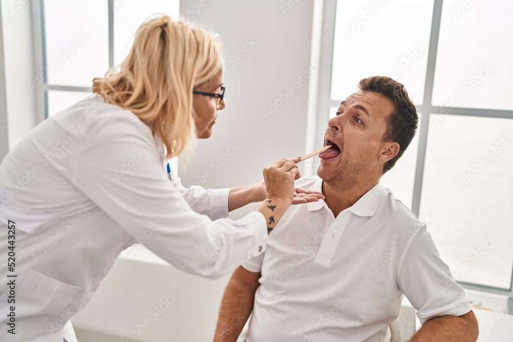 Middle age man and woman doctor and patient examining throat having medical consultation at clinic Middle age man and woman doctor and patient examining throat having medical consultation at clinic