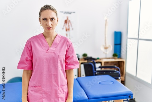 Young blonde woman working at pain recovery clinic skeptic and nervous  frowning upset because of problem. negative person.