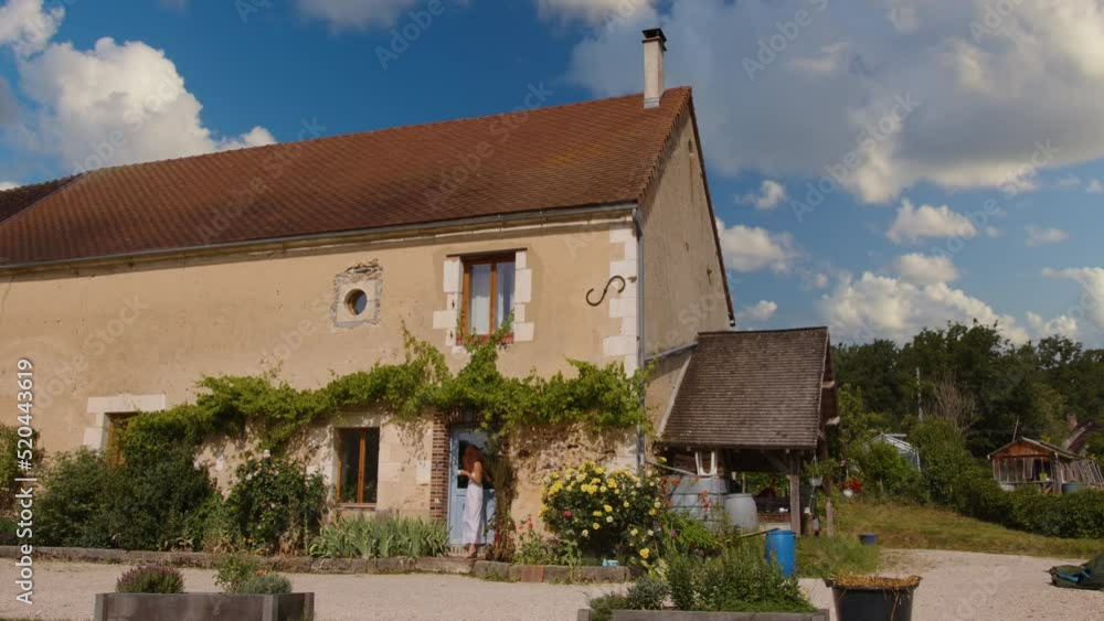 French morning in Provence near Paris. A girl in a white dress walks on the threshold of a French old house with a cup of coffee and a croissant