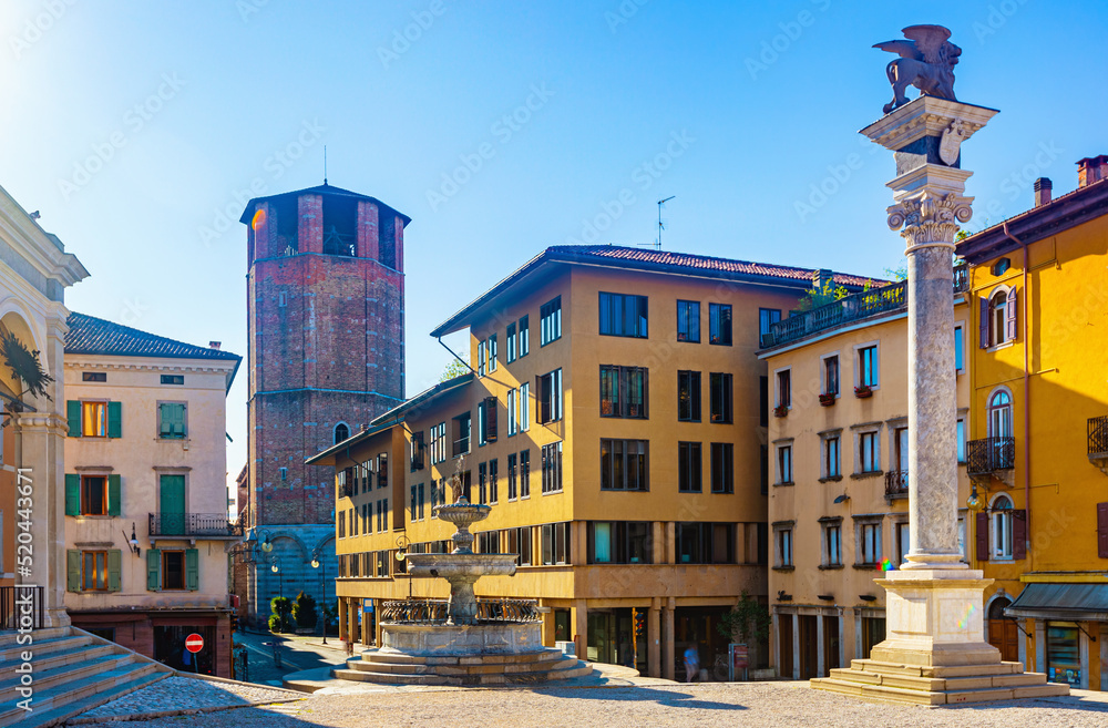 View of Piazza liberta - central square of Udine city with ancient fountain and Column bearing Venetian Lion, Italy