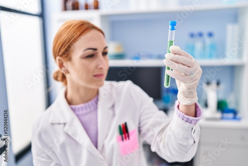 Young caucasian woman scientist measuring liquid at laboratory
