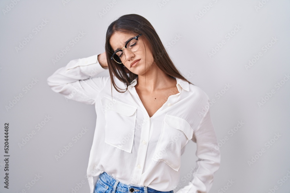 Young brunette woman wearing glasses suffering of neck ache injury, touching neck with hand, muscular pain Young brunette woman wearing glasses suffering of neck ache injury, touching neck with hand, muscular pain