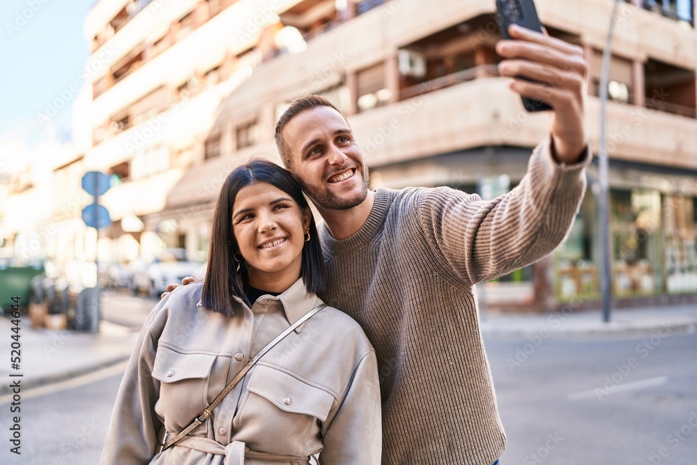 Naklejka premium Man and woman couple smiling confident making selfie by the smartphone at street