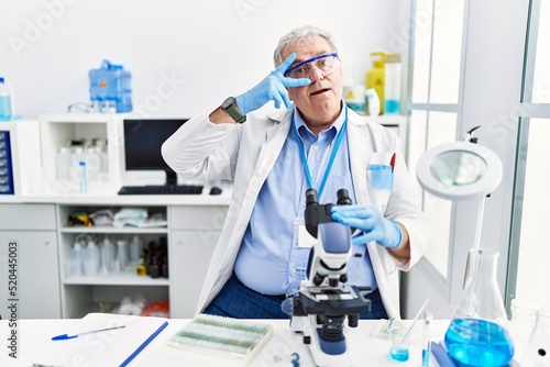 Senior caucasian man working at scientist laboratory doing peace symbol with fingers over face  smiling cheerful showing victory