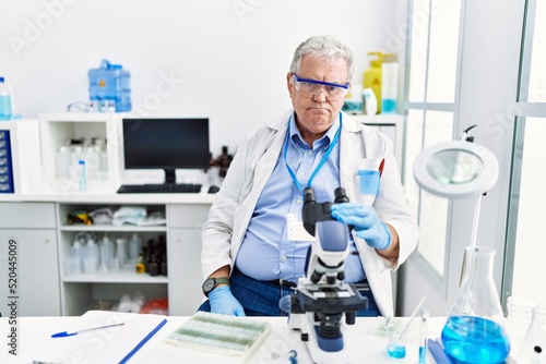 Senior caucasian man working at scientist laboratory depressed and worry for distress, crying angry and afraid. sad expression.