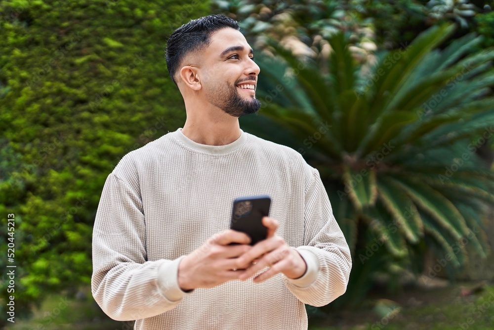 Young arab man smiling confident using smartphone at park