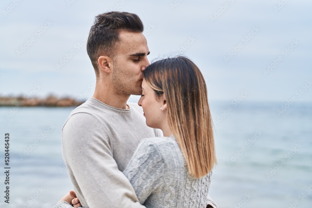 Man and woman couple hugging each other kissing at seaside Man and woman couple hugging each other kissing at seaside