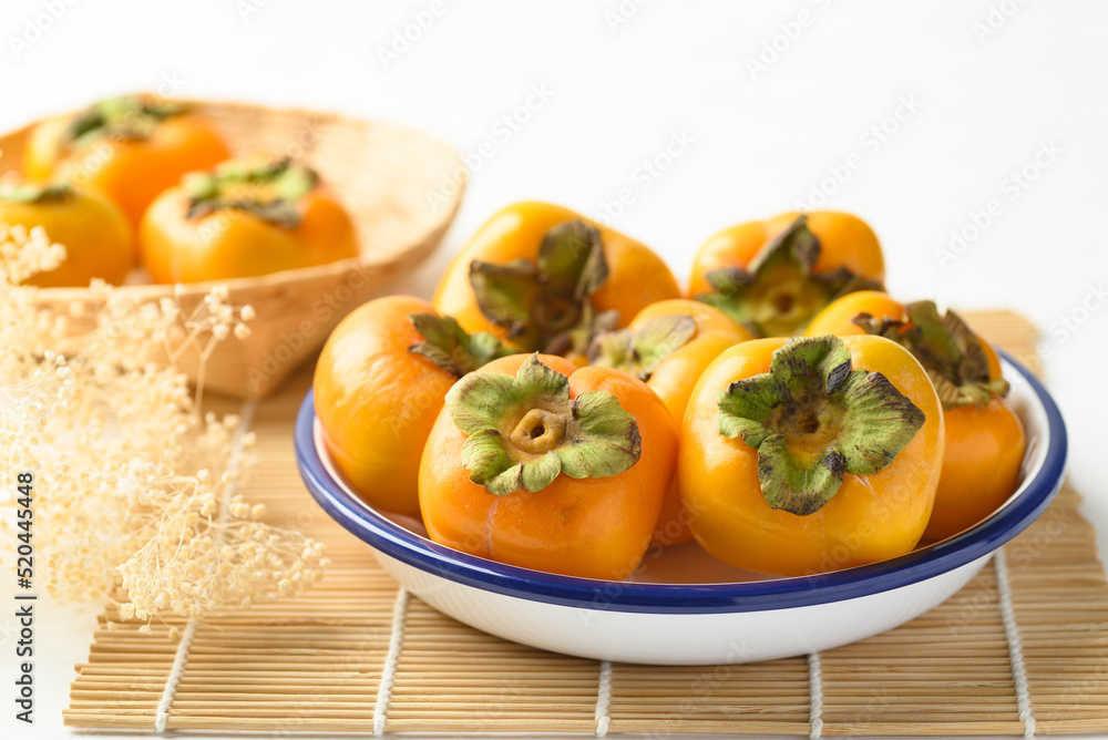 Ripe persimmon fruit in bowl on white background Ripe persimmon fruit in bowl on white background