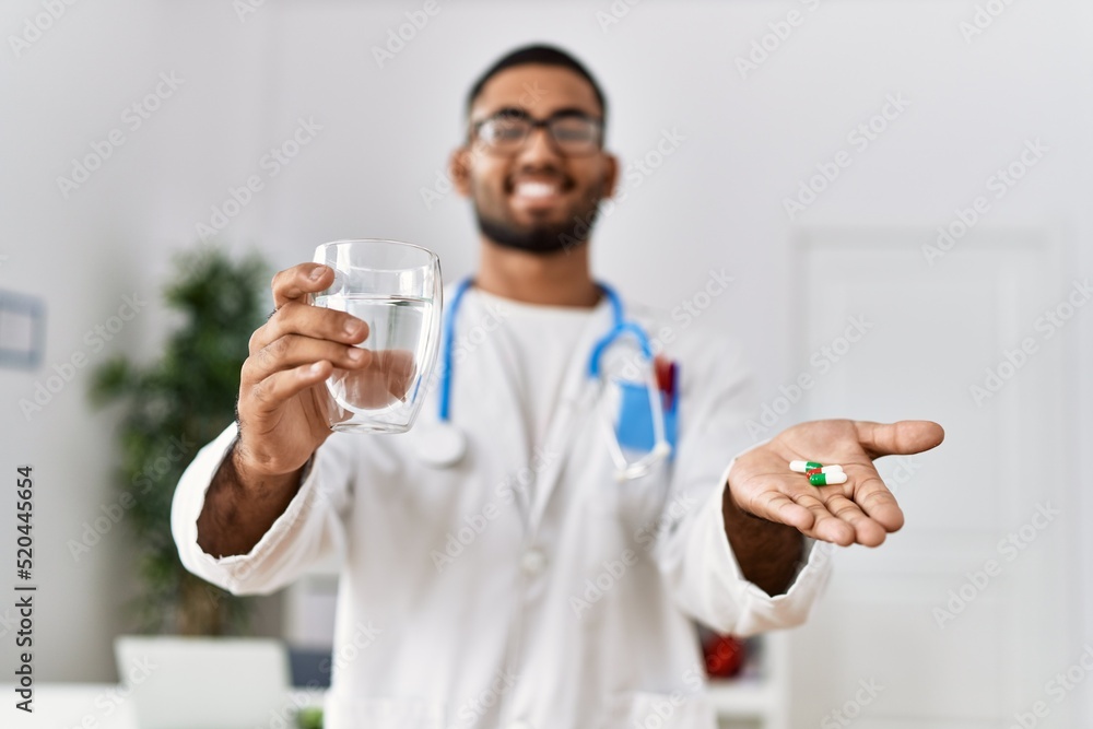 Young arab man wearing doctor uniform holding pills at clinic Young arab man wearing doctor uniform holding pills at clinic