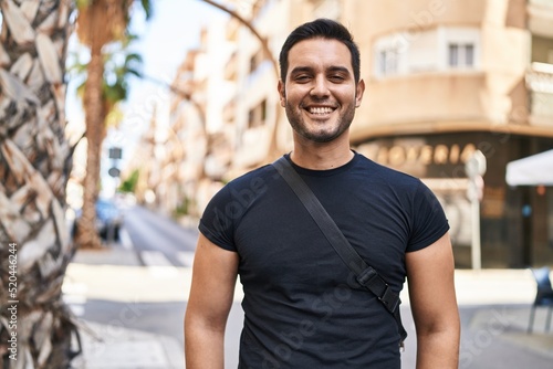 Young hispanic man smiling confident standing at street