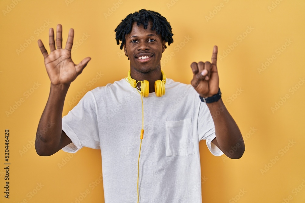 Young african man with dreadlocks standing over yellow background showing and pointing up with fingers number six while smiling confident and happy. Young african man with dreadlocks standing over yellow background showing and pointing up with fingers number six while smiling confident and happy.
