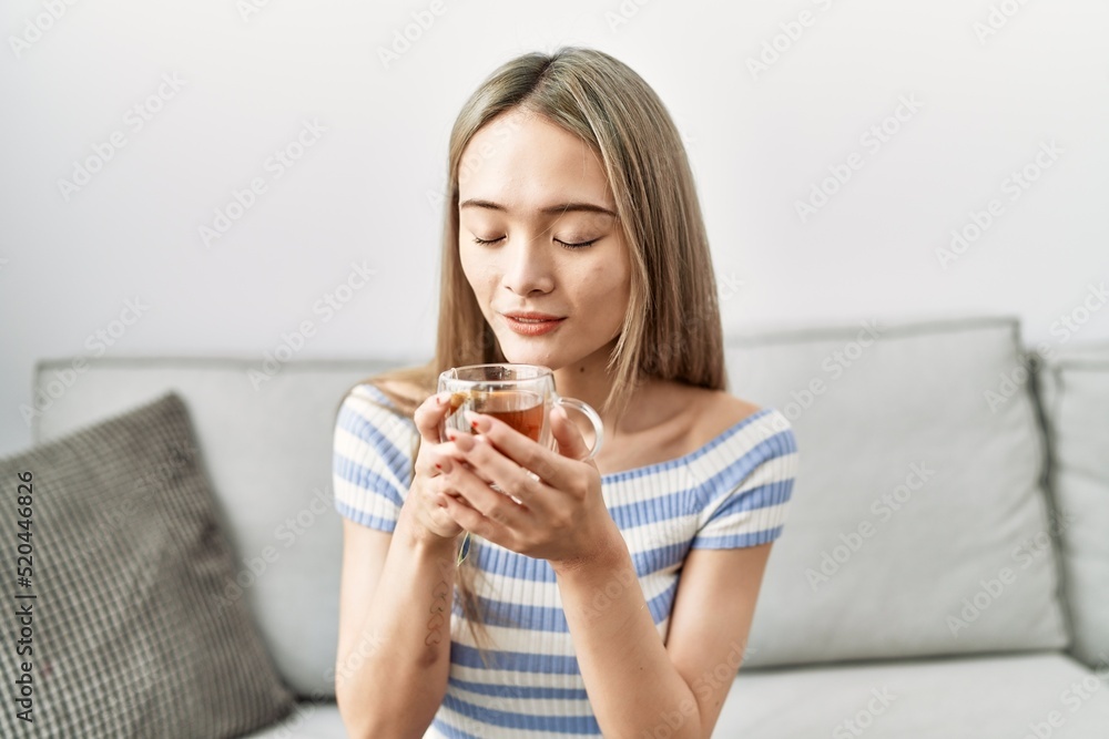 Young chinese woman smiling confident drinking tea at home Young chinese woman smiling confident drinking tea at home