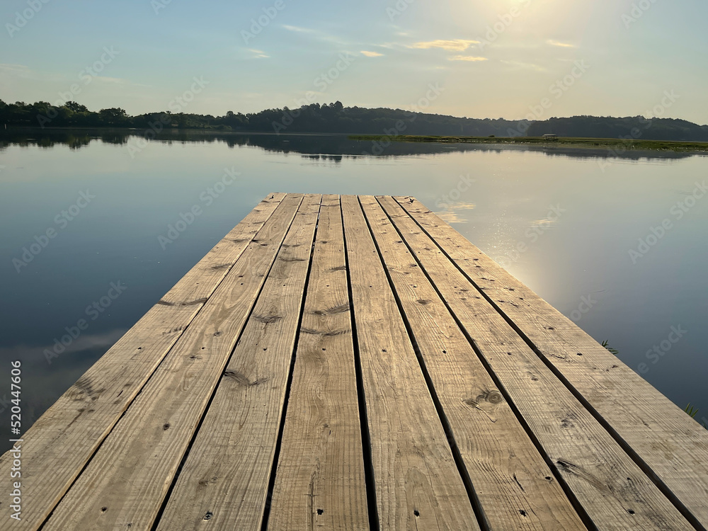 Wooden boat dock with sun reflection on lake water