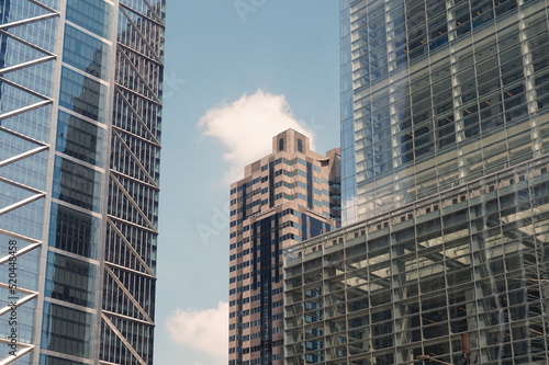 Contemporary Modern Skyscrapers with Glass Windows, Reflections, Blue Sky and White Clouds