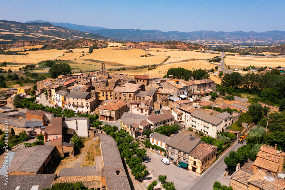 Scenic aerial view of small Spanish town of Figuerola dOrcau on top of hill with agricultural lands in background on sunny summer day, Catalonia